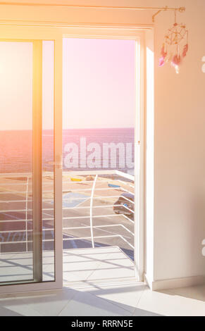 Blick auf den Balkon mit deckenhohen Fenstern und offene Schiebetür im Sonnenlicht Stockfoto