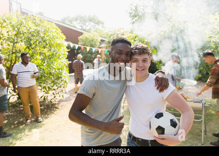 Portrait zuversichtlich, dass junge Männer mit Fußball genießen Garten Grill Stockfoto