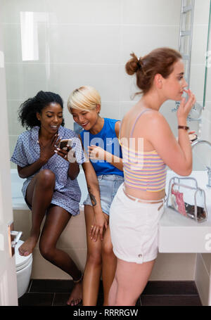 Junge Frauen Mitbewohner mit Smart Phone und in der Wohnung Badezimmer bereit Stockfoto