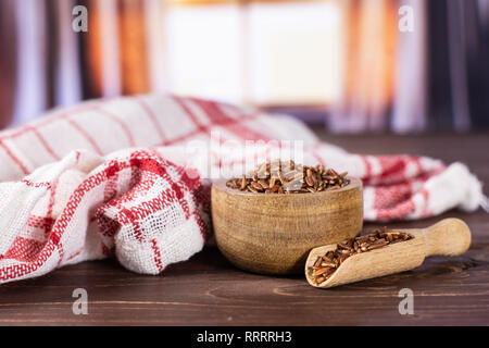 Menge ganze rohe rote Reis Geschirrtuch mit Holzschale mit seidenen Vorhängen hinter Stockfoto