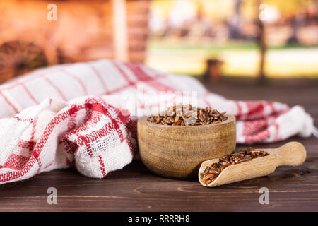 Menge ganze rohe rote Reis Geschirrtuch mit Holzschale mit Karre im Hintergrund Stockfoto