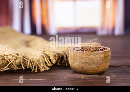 Menge ganze rohe rote Reis Jute-stoff mit Holzschale mit seidenen Vorhängen hinter Stockfoto