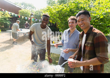 Porträt Lächeln männliche Freunde genießen Sommer Garten Grill Stockfoto