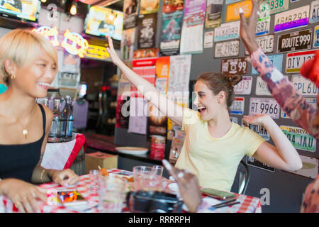 Begeisterte junge Frauen Freunde jubeln in bar Stockfoto