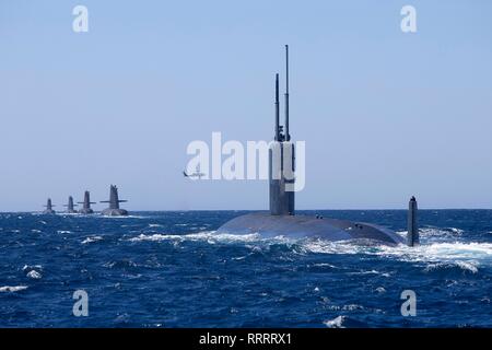 Die US-Marine Los Angeles-Klasse Angriffs-U-Boot USS Santa Fe Segel, die sich in der Ausbildung mit der Royal Australian Navy Collins klasse u-Boote HMAS Collins, HMAS Farncomb, HMAS Dechaineux und HMAS Sheean, als australischer MH-60R Seahawk Hubschrauber Overhead in der West Australian übung Bereich Februar 18, 2019 vor der Küste von Fremantle, Australien fliegt. Stockfoto