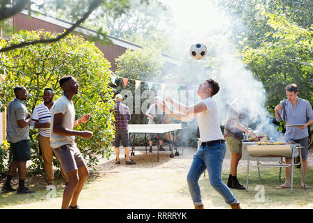 Männliche Freunde spielen Fußball und Tischtennis, Garten Grill genießen. Stockfoto