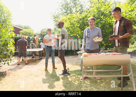 Männliche Freunde Grillen im sonnigen Sommer Hinterhof Stockfoto