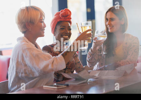 Glückliche, unbeschwerte junge Frauen Freunde toasten cocktail Gläser in bar Stockfoto