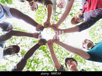 Ansicht von unten mens Gruppe beitreten Fäuste im Kreis, Wandern unter Bäumen Stockfoto