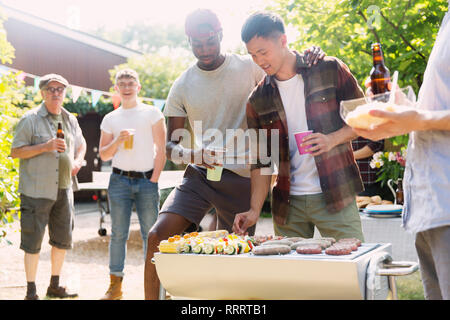 Männliche Freunde genießen Grill im sonnigen Sommer Hinterhof Stockfoto