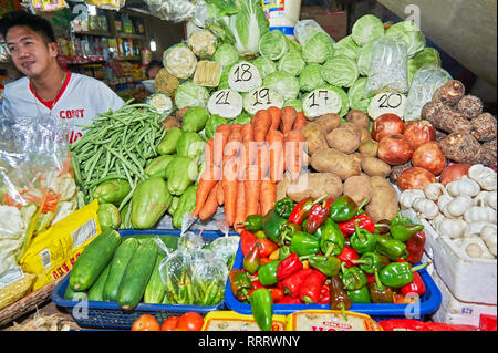 Stadt Puerto Princesa, Palawan, Philippinen - 11. März 2011: Junge männliche Verkäufer in einem Stall am zentralen Markt verkaufen frisches Gemüse, Lebensmittelgeschäft Stockfoto