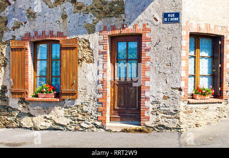 Ein Haus mit zwei Fenstern mit Fensterläden aus Holz und braunen Tür auf der Rue de L'avenir Straße im Zentrum einer kleinen Stadt Neuvy-en-Mauges, Frankreich. Warme s Stockfoto