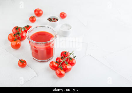 Glas frischen Bio Tomatensaft mit rohen Tomaten auf hellen Hintergrund. Bloody Mary cocktail Stockfoto