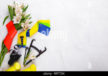 Ansicht von oben Bild von Kurzhanteln, bunte elastische Gummi Expander, Bremssättel und Maßband auf einem weißen strukturierten Hintergrund. Gesunder Lebensstil, Fitnessraum und nicht Stockfoto