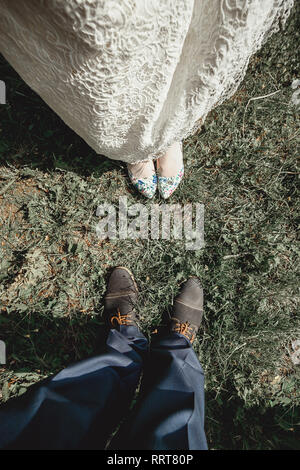 Blick von oben auf die stilvolle Bräutigam und Braut Fuß in der elegante Schuhe auf Gras. Hochzeit Fashion Concept. Stockfoto