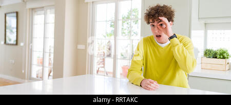 Wide Angle Shot junger stattlicher Mann zu Hause ok Geste mit Gesicht überrascht, schockiert, Auge durch die Finger schauen. Die ungläubigen Ausdruck. Stockfoto