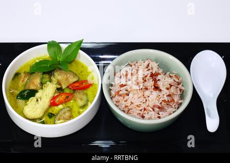 Thailändisches Grünes Curry Huhn serviert mit braunem Reis. Stockfoto