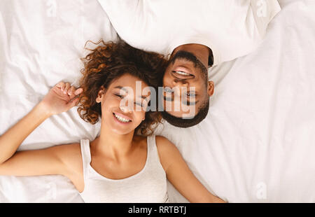 Junge Liebespaar im Bett liegend zusammen und Suchen an Kamera Stockfoto