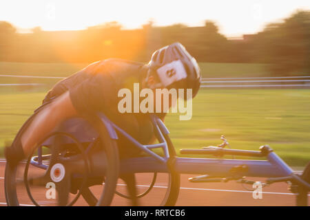 Entschlossene junge weibliche paraplegic Athlet Beschleunigung zusammen Sport Track im Rollstuhl Rennen Stockfoto