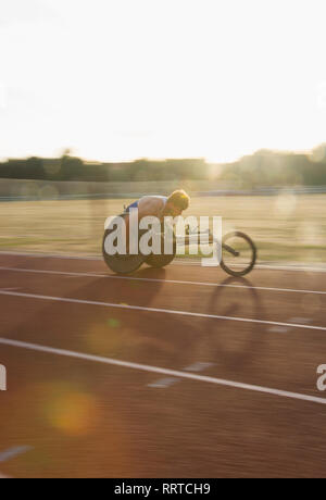 Bestimmt jungen männlichen querschnittsgelähmten Athlet Beschleunigung zusammen Sport Track im Rollstuhl Rennen Stockfoto