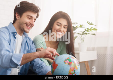Glückliches Paar bei Globe suchen, wählen Land zu besuchen Stockfoto