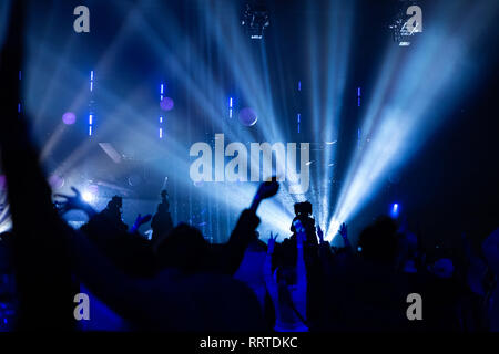 Silhouetten von einem Konzert Masse und Kameramann vor dem Hintergrund der hellen, farbigen Strahlen auf die Bühne. Kamera mit dem Operator ist auf der Pla Stockfoto