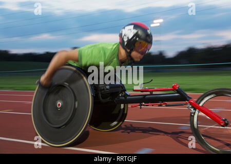 Bestimmt jungen männlichen querschnittsgelähmten Athlet Beschleunigung zusammen Sport Track im Rollstuhl Rennen Stockfoto