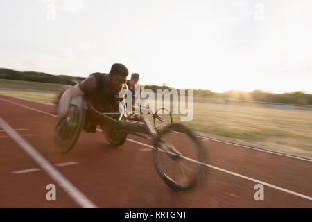 Bestimmt jungen männlichen querschnittsgelähmten Athlet Beschleunigung zusammen Sport Track im Rollstuhl Rennen Stockfoto