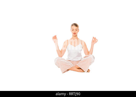 Mädchen im Schlafanzug meditieren in der Luft isoliert auf weißem Stockfoto