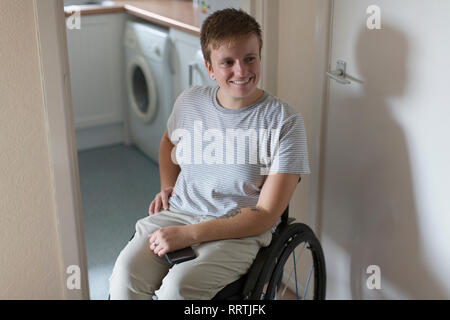 Lächelnde junge Frau im Rollstuhl zu Hause Stockfoto