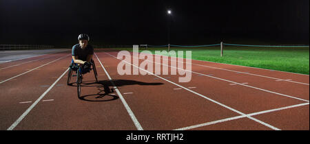Portrait zuversichtlich , Junge weibliche paraplegic Athlet Training für Rollstuhl Rennen am Sportplatz in der Nacht Stockfoto