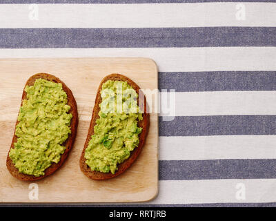 Guacamole Sandwich auf hellen Hintergrund avocado Sandwiches auf Holzbrett und textile Draufsicht Stockfoto