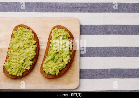 Sandwich mit Guacamole auf Licht textil Draufsicht. Sandwiches auf Holzbrett Stockfoto