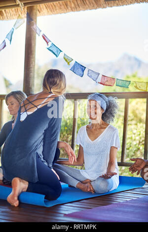 Weibliche Ausbilder im Gespräch mit Studenten in der Hütte während Yoga Retreat Stockfoto