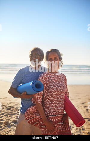 Portrait happy senior Paar mit Yoga Matten auf Sunny Beach Stockfoto