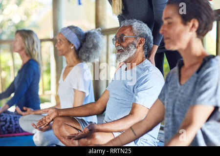 Serene älterer Menschen meditieren während Yoga Retreat Stockfoto