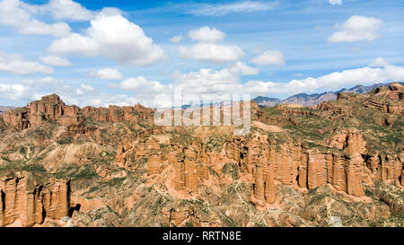 Luftaufnahme von Binggou Danxia Canyon Relief in Zhangye, Sunan Region, Provinz Gansu, China. Rote Sandsteinfelsen im Geopark. Niedrige Wolken und Blau Stockfoto