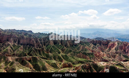 Luftaufnahme von Binggou Danxia Canyon Relief in Zhangye, Sunan Region, Provinz Gansu, China. Scharfe Spitzen Spitzen im Geopark. Niedrige Wolken und Blau Stockfoto