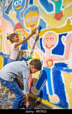 Kinder malen lebendige Wandbild an sonnigen Wand Stockfoto