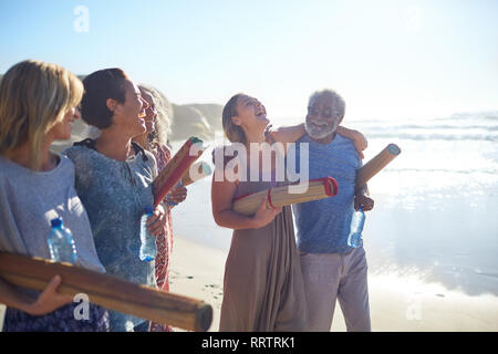 Gerne Freunde mit Yogamatten kleben an sonnigen Strand während Yoga Retreat Stockfoto