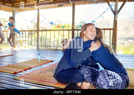 Glückliche Mutter und Tochter umarmen auf Yoga Matten in der Hütte während Yoga Retreat Stockfoto