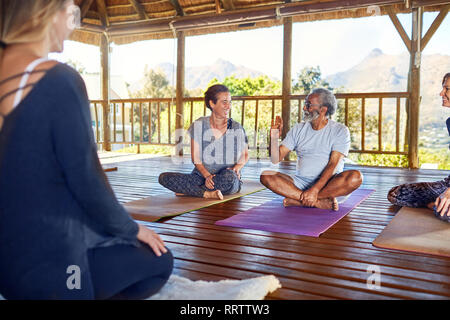 Mann und Frau sprechen während der Yogastunde in der Hütte auf Yoga Retreat Stockfoto