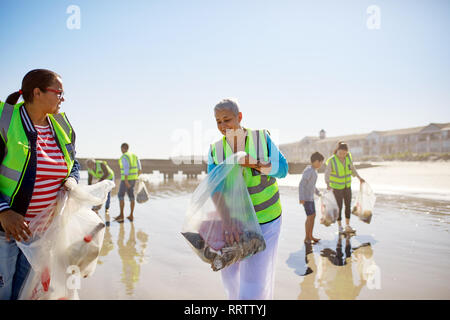 Freiwillige Reinigung Wurf auf sonnigen, nassen Sand Strand Stockfoto