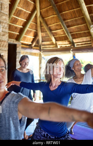 Selbstbewusste Frau üben Krieger 2 Pose in der Hütte während Yoga Retreat Stockfoto