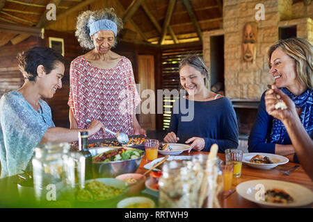 Freunde genießen gesunde Mahlzeit in der Hütte während Yoga Retreat Stockfoto
