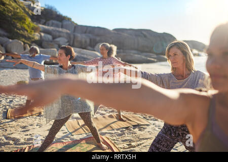 Gruppe Yoga üben an sonnigen Strand während Yoga Retreat Stockfoto