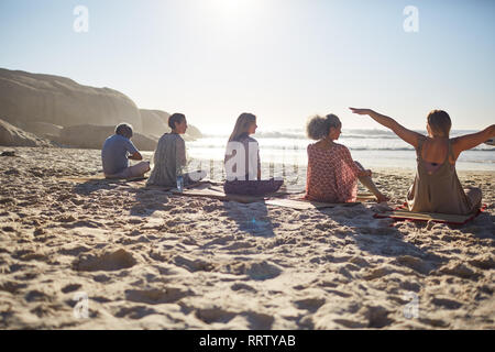 Gruppe sitzen auf Yoga Matten an sonnigen Strand während Yoga Retreat Stockfoto