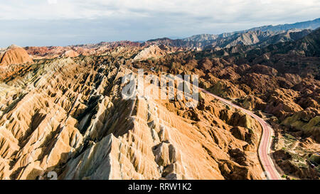 Rainbow Bergen geologischen Park. Stripy Zhangye Danxia Relief geologischen Park in der Provinz Gansu, China. Touristenbusse auf einer Straße in einem Tal auf einer S Stockfoto