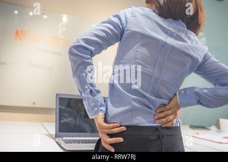 Junge Geschäftsfrau leiden unter Rückenschmerzen im Büro Stockfoto