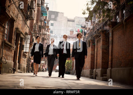Vier Kollegen gehen Seite an Seite eine Straße der Stadt. Stockfoto